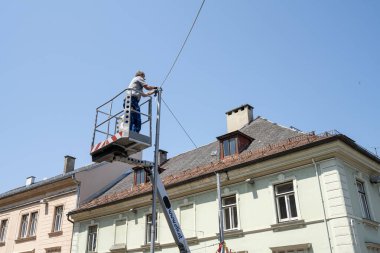 Villach, Avusturya. 18 Temmuz 2023. Şehir merkezindeki bir sokakta elektrik kabloları üzerinde çalışırken bir teknisyen sepeti kaldırdı.