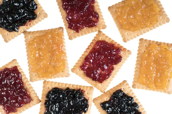 Some dry biscuits with jam on a white surface