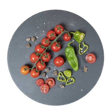 bir taş tabak üzerinde bazı küçük domates ve yeşil biber