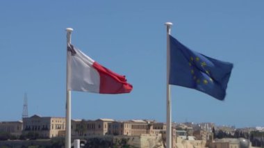Valletta, Malta, 3 Nisan 2024. Mavi gökyüzünde dalgalanan Malta ve Avrupa Birliği bayrakları