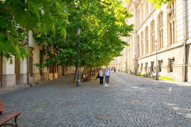Bükreş, Romanya. 24 Mayıs 2024. İnsanlar tarihi şehir merkezindeki banklarda dinleniyorlar.