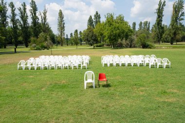 boş beyaz sandalye ve boş kırmızı sandalye seyircilerin önünde parkta.