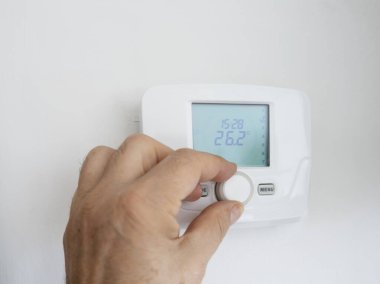 Bir evin ısıtma termostatını ayarlayan bir erkek el.