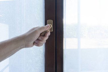 Bir erkek eli pencereyi kapatıyor.