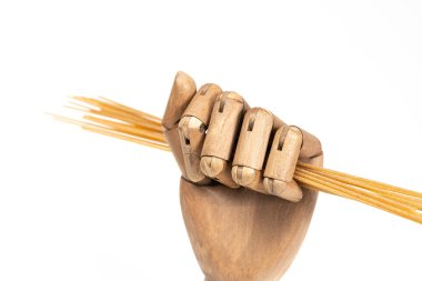 Beyaz arka planda ahşap bir el içinde tam buğday spagettisi.