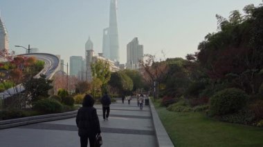 Şangay, Çin. 8 Ocak 2025. Arka planda Pudong finans merkezi binaları olan bir şehir merkezi parkında yürüyüş.