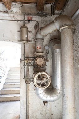 Terk edilmiş bir endüstriyel yapıda ölçüm ve kontrol araçlarına sahip eski borular.