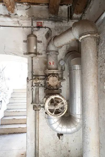 Terk edilmiş bir endüstriyel yapıda ölçüm ve kontrol araçlarına sahip eski borular.