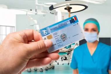İtalya. 22 Haziran 2025. İtalyan ulusal sağlık kartı elinde bir hastane ameliyathane görüntüsü ve arka planda bir doktor var.