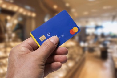 Italy, june 22, 2025. Mastercard brand credit card in in the hand with a luxury shop in the background
