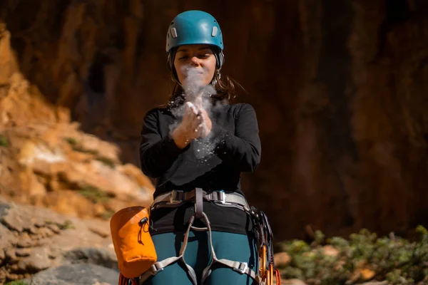 stock image A young girl is getting ready for mountain climbing, training and taking chalk from her bag, clapping her hands. A woman with climbing equipment is involved in active extreme sports, mountaineering.