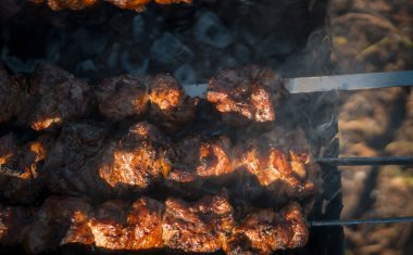 Sosu ve baharatı olan sulu büyük et parçaları, kömürlerin üstünde kızartılıyor lezzetli kokulu kebap, ızgara barbekü yakın çekim manzarası.