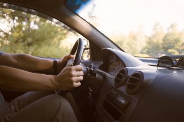 Genç bir adam arabasıyla yola çıkıyor, gün batımında yol boyunca sürüyor, direksiyonu elleriyle tutuyor, yakından bakıyor..