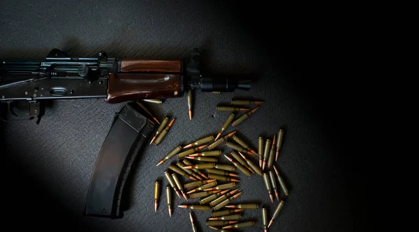 AKS-74U assault rifle and cartridges 5.45 for it lie on a dark background, a firearm with a magazine, a concept on a military army theme and weapons.