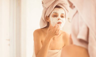 Kafasına ve vücuduna havlu geçirmiş genç bir kız banyoda aynanın yanında duruyor ve yüzüne kilden bir maske takıyor. Kadın sağlığına ve güzelliğine dikkat ediyor..