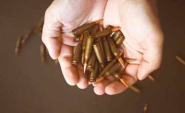 Erkek eli bir avuç cephaneyi tutuyor. Elinde mermiler var. Arka planda, yakın çekimde. Konsept, savaş, ordu ve ekonomik krizle ilgili karmaşık çatışmalardır..