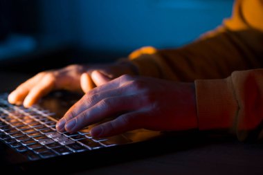 Erkek eller dizüstü bilgisayarda klavye kullanıyor, bir adam çalışıyor, bir iş kuruyor, çalışıyor, geceleri bilgisayar oyunu oynuyor. Yakın çekim görünümü.