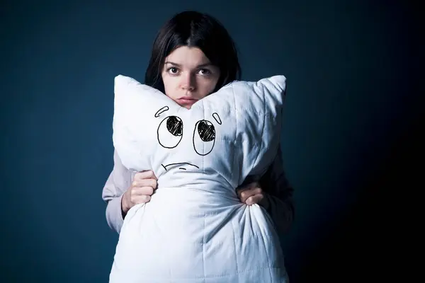 stock image Funny girl with disgruntled offended face hugs a pillow. Young woman did not sleep well, she has trouble sleeping, woken up. Health problems with insomnia, need an orthopedic pillow, self-care, rest.