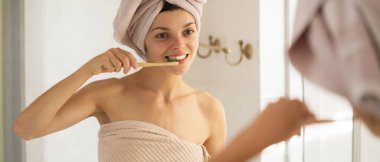 Genç bir kız banyoda dinlendikten sonra dişlerini aynanın yanında fırçalar, kadın havluya sarılır ve vücudunun ve dişlerinin sağlığıyla ve güzelliğiyle ilgilenir..