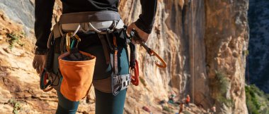A young girl is engaged in active sports, rock climbing and mountaineering. A woman looks at a beautiful red rock and takes magnesia in her hand, getting ready for training and climbing.