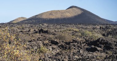 Fosilleşmiş karanlık lav, taşlar, kayalar, dağlar ve Kanarya Adaları 'ndaki Lanzarote Ulusal Parkı' ndaki volkanik manzaralar..