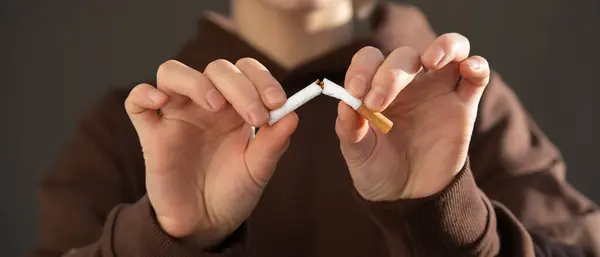 Genç bir kız sigarasını elinde kesin bir şekilde kırar, yakın çekim görüntüsü, bir kadın nikotin bağımlılığından kurtulur ve sağlıklı bir yaşam tarzı seçer, güzelliğine ve sağlığına dikkat eder..