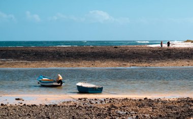 Küçük balıkçı tekneleri, güneşli bir günde körfeze demirlemiş motorlu botlar, okyanus ve yatlarla dolu deniz manzarası..