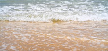 Altın sarısı kumu ve dalgalı turkuaz okyanus suyuyla güzel, temiz bir sahil. Güneşli bir günde insansız bir sahil şeridi..