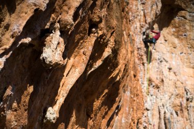 Tırmanma ekipmanlarıyla, kaya ayakkabılarıyla, iple, magnezyayla dağa tırmanan genç bir adam, kaya tırmanışı, dağcılık, aşırı aktif sporlarda yer alıyor..