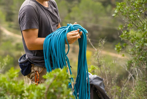 Человек с верёвкой, карабкающийся в горах. Восхождение в горах Испании. Техническое альпинизм.