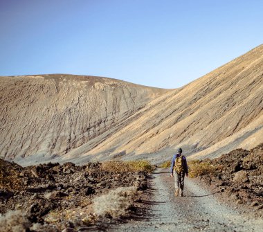 Genç bir adam aktif bir hayat sürüyor, vadide geziyor, çöldeki resimli kum dağları ve volkanların arasında yürüyor..