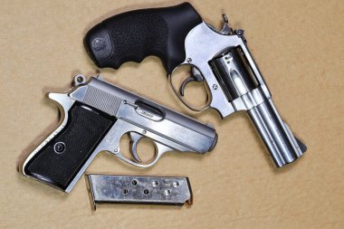 Kısa namlulu tabanca, paslanmaz çelik J-frame m60 tabanca ve kahverengi arka planda izole edilmiş yarı otomatik tabanca PPK 'leri..
