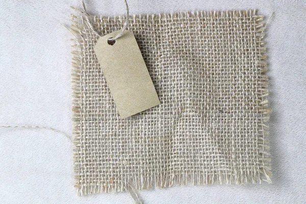 stock image Blank tag tied with natural material string. Price tag, gift tag, sale tag, address label on Brown coarse sackcloth texture, burlap texture background, sack Texture.