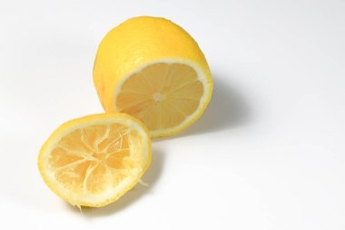 Yarısı kesilmiş taze ve sıkılmış limon meyvesi beyaz arka planda izole edilmiş..