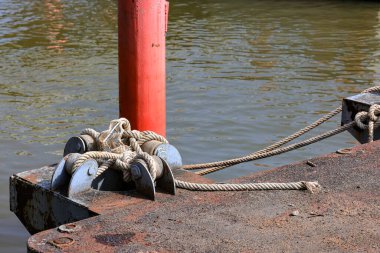 Mooring line on rusty pier referred to a post on a ship or quay. clipart