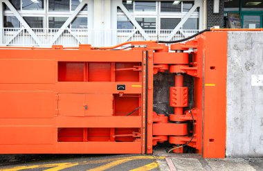 Limandaki büyük kırmızı kapının hidrolik menteşesi, su tutma ve liman trafiği için çelik kapı.