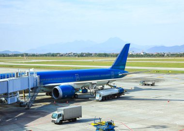 Yer Servisi yakıt kamyonu hava sahasında mavi bir uçak dolduruyor..