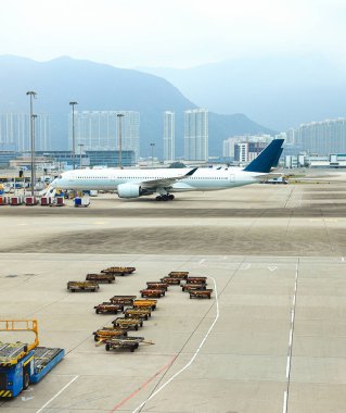 Ground support equipment, Baggage Tug( baggage dolly transport ) standby for services in Apron near aircraft bay. clipart