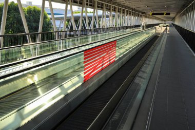 Otomatik yürüyen merdiven ya da Travelator yürüyüş yolunun kırık ya da kırık cam duvarı için ahhok onarımı. Kırık cam duvar koridorunu gizlemek için kırmızı bant.. 