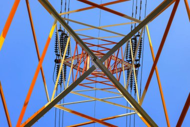 Mavi gökyüzüne karşı yüksek voltajlı elektrik kulesinin altından görüntüle.