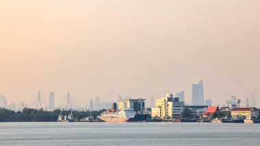 Bangkok nakliye konteynır terminalinde okyanus gemileri Asya 'nın liman ve küresel ticareti modernleştirdiği bulutlu bir günde Bangkok şehir manzaralı bir arka plan..