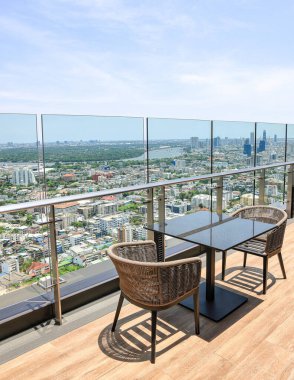 Bir gökdelenin tepesinde rahat bir oturma alanı, çatı katı bar ve restoran alanında güzel şehir manzarası olan servis alanı.