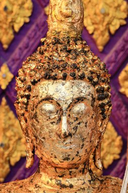 Merhametli yüzüyle altın yapraklı Antik Buda heykeli.