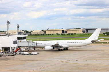 Yolcu kapısındaki beyaz ticari uçak parkı, Jet Bridge 'e bağlanın. Yer hizmetleri ekibi tarafından hizmet edilmek.