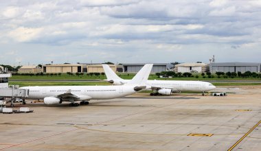 Beyaz ticari uçaklar uçak römorkörleri tarafından taksiye geri itiliyor..