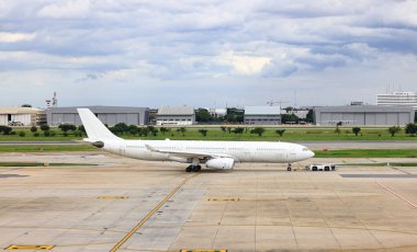 Beyaz ticari uçaklar uçak römorkörleri tarafından taksiye geri itiliyor..