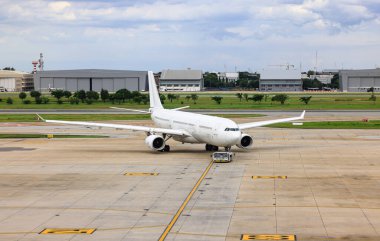 Beyaz ticari uçaklar uçak römorkörleri tarafından taksiye geri itiliyor..