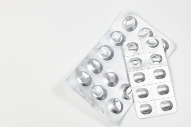 Bazı kullanılmış ilaç paketleri, tıbbi ilaçlar ve gümüş renkli parlak paketler beyaz arka planda izole edilmiş..