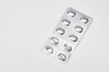 Bazı kullanılmış ilaç paketleri, tıbbi ilaçlar ve gümüş renkli parlak paketler beyaz arka planda izole edilmiş..