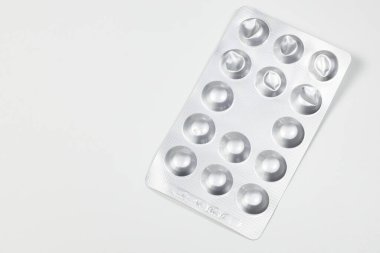 Bazı kullanılmış ilaç paketleri, tıbbi ilaçlar ve gümüş renkli parlak paketler beyaz arka planda izole edilmiş..